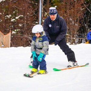 señor grande y niño esquiando en bautismo de nieve en ushuaia